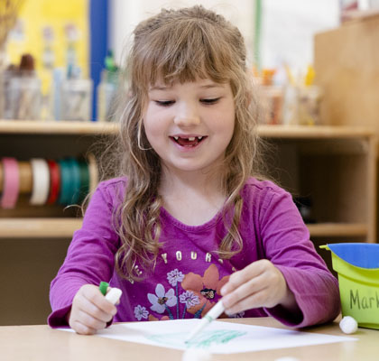 Young girl with purple shirt coloring