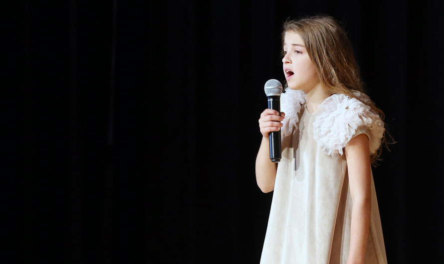 girl singing on stage with a microphone