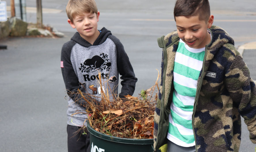 boys holding a bin full of sticks