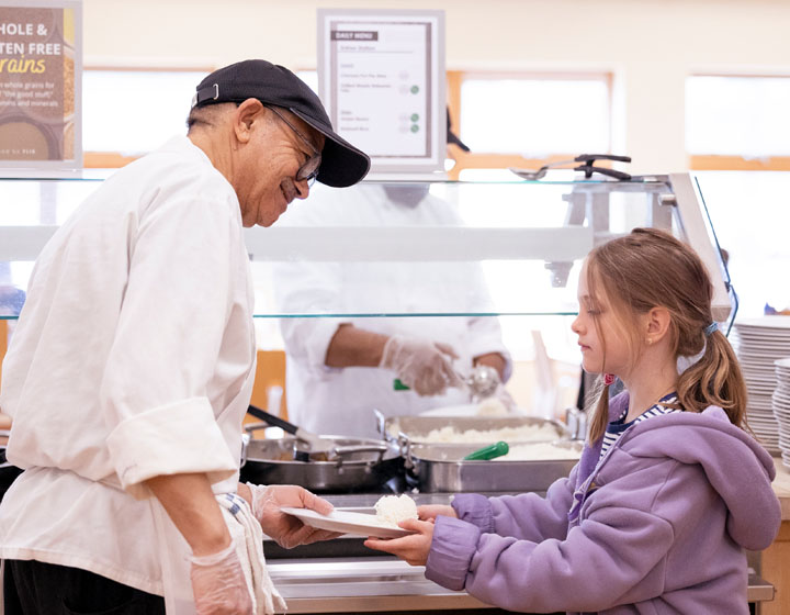 Food service staff serving a child lunch