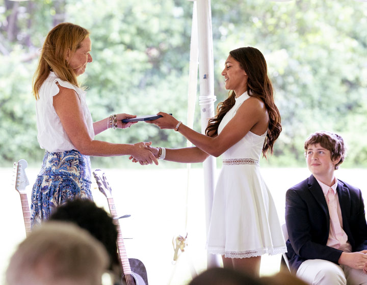 woman handing a diploma to graduate