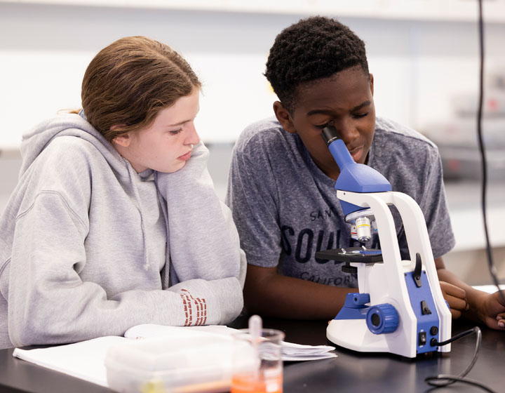 boy looking through microscope next to girl
