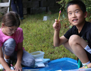 boy smiling holding up pencil